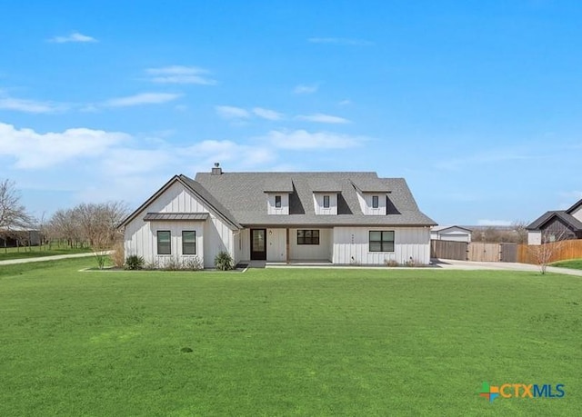 modern farmhouse style home with board and batten siding, roof with shingles, a front lawn, and fence