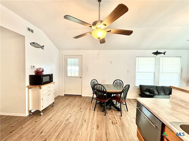 dining room featuring light wood-type flooring, vaulted ceiling, and ceiling fan