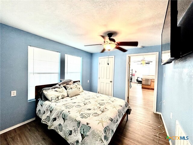 bedroom with dark wood-type flooring, ceiling fan, a textured ceiling, and a closet