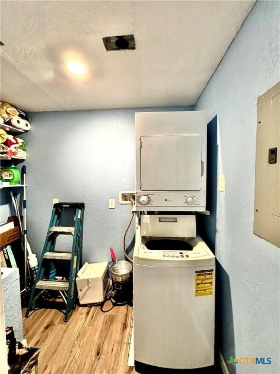 101 N 13th St, Seadrift, TX 77983 - laundry room featuring stacked washing machine and dryer, light wood-style flooring, a textured ceiling, electric panel, and a textured wall