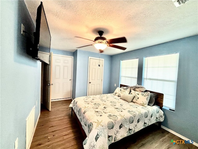 bedroom with dark wood-type flooring, a textured ceiling, and ceiling fan