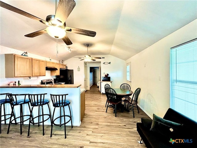 101 N 13th St, Seadrift, TX 77983 - kitchen featuring freestanding refrigerator, light wood finished floors, ceiling fan, vaulted ceiling, and a breakfast bar area