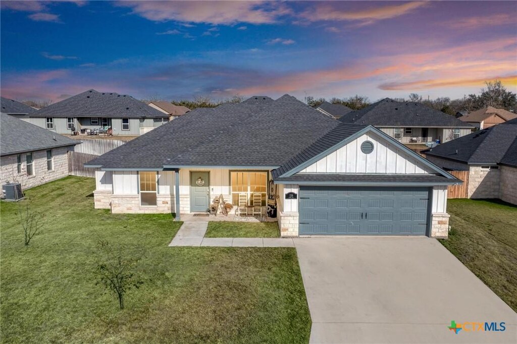 116 Elmer Ave, Burnet, TX 78611 - ranch-style house with board and batten siding, stone siding, driveway, and an attached garage