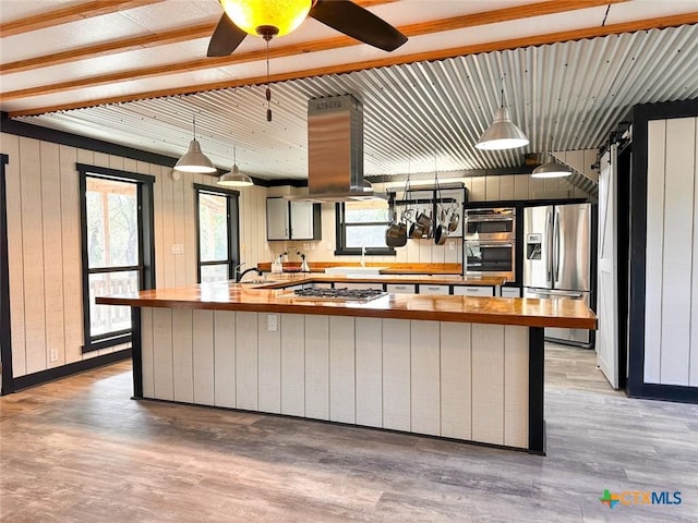 kitchen featuring wooden counters, decorative light fixtures, island range hood, light hardwood / wood-style flooring, and stainless steel appliances