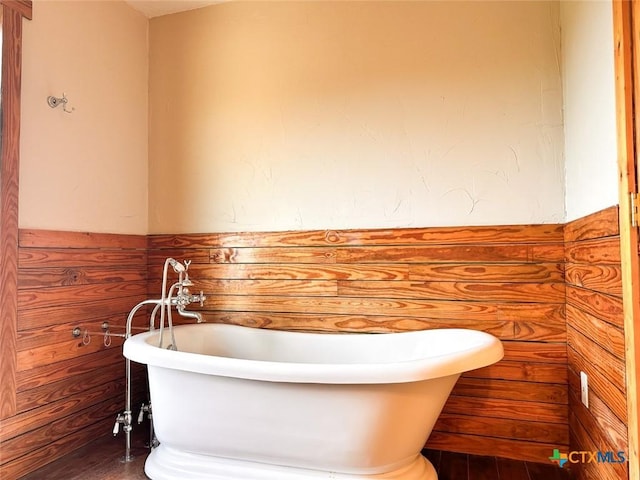 bathroom with a washtub and wooden walls