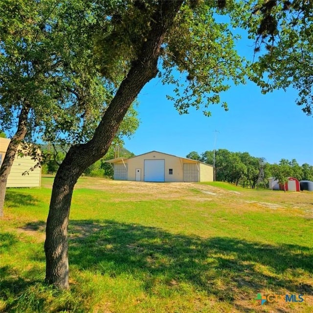 view of yard with a garage and an outbuilding