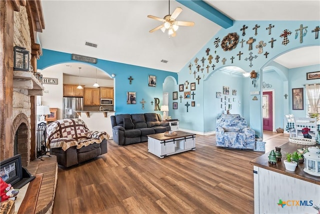 living room with beam ceiling, a brick fireplace, wood finished floors, and visible vents