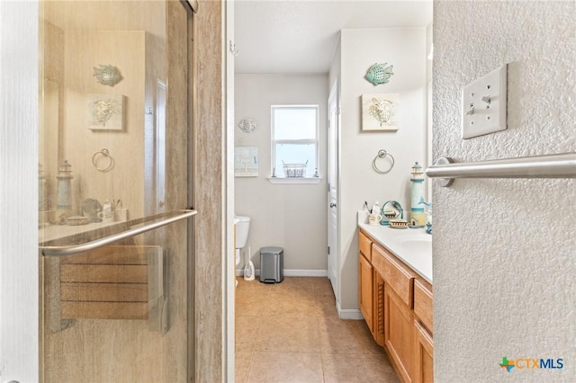 bathroom with tile patterned flooring, toilet, vanity, baseboards, and a stall shower