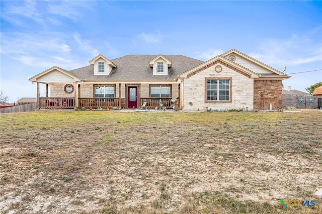 view of front of property featuring a front yard, stone siding, and fence