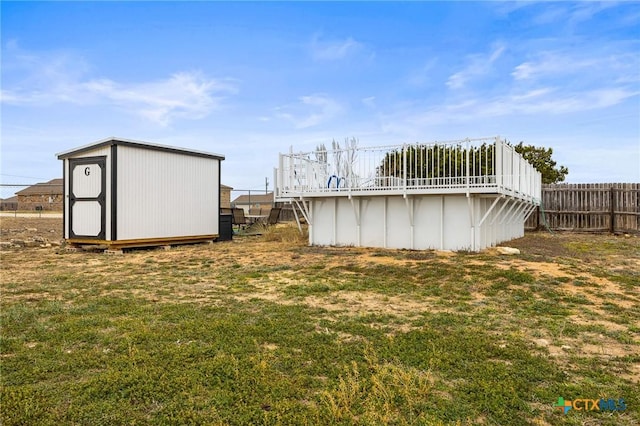 view of yard with a pool, an outbuilding, fence, and a storage shed