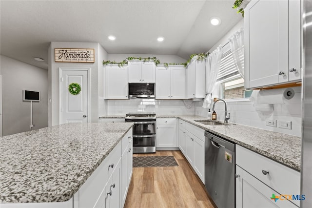 31682 Nimbus Dr, Bulverde, TX 78163 - kitchen with stainless steel appliances, a sink, light wood-type flooring, white cabinets, and backsplash