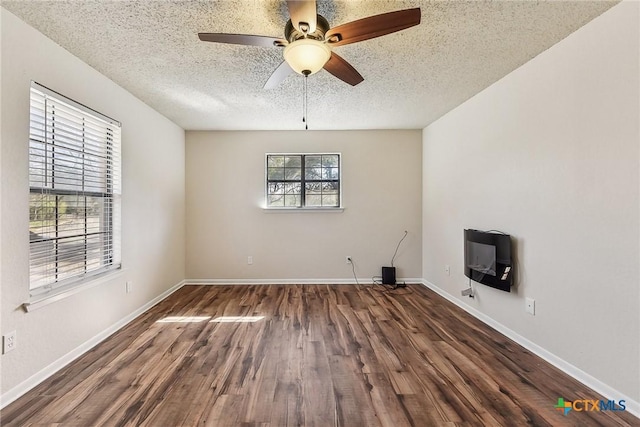 spare room featuring ceiling fan, dark hardwood / wood-style floors, heating unit, and a textured ceiling