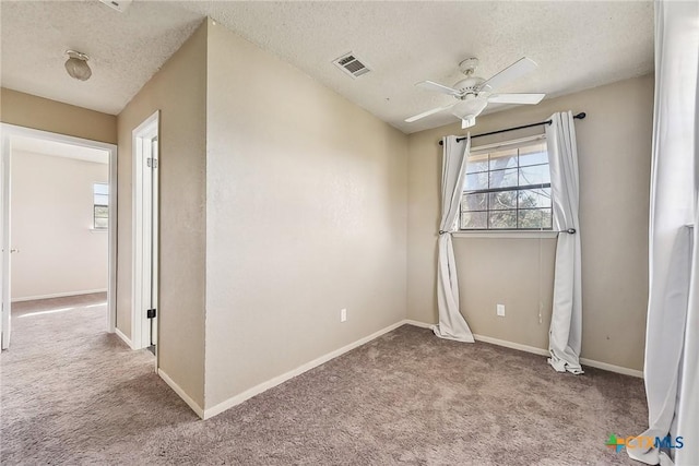 empty room featuring ceiling fan, light colored carpet, and a textured ceiling