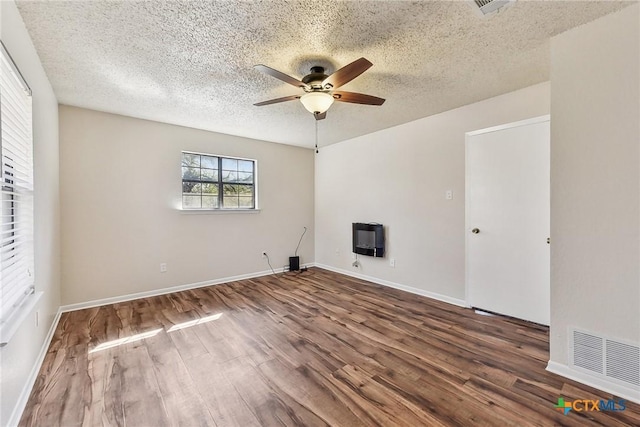 spare room with ceiling fan, hardwood / wood-style floors, heating unit, and a textured ceiling