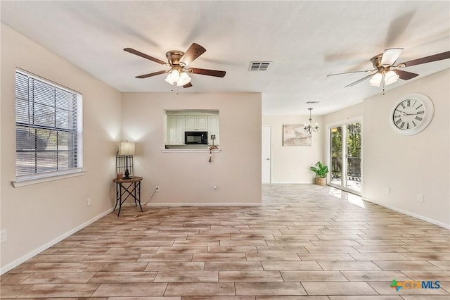 unfurnished room featuring ceiling fan with notable chandelier and light hardwood / wood-style flooring