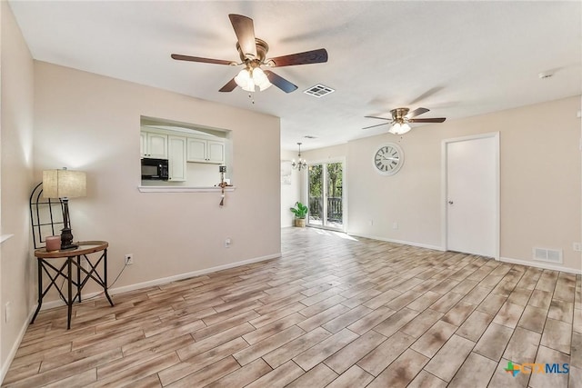 unfurnished living room featuring ceiling fan with notable chandelier and light wood-type flooring