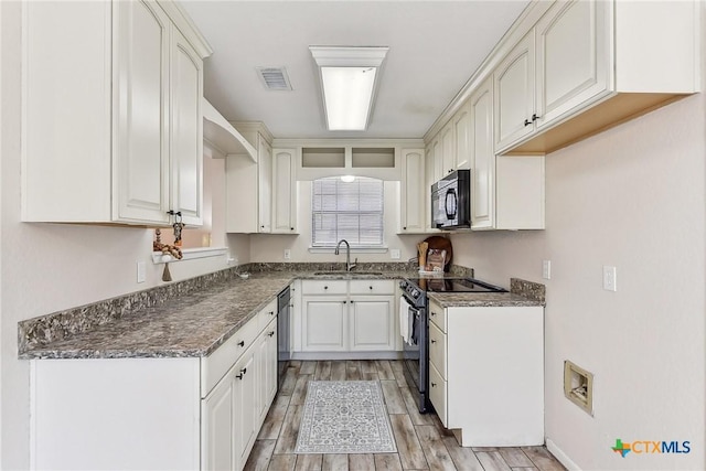 kitchen with white cabinetry, dark stone counters, sink, and black appliances