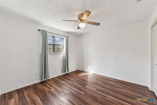 empty room with ceiling fan, dark wood-type flooring, and a textured ceiling