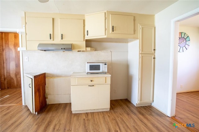 kitchen featuring range hood, cream cabinets, and light hardwood / wood-style flooring