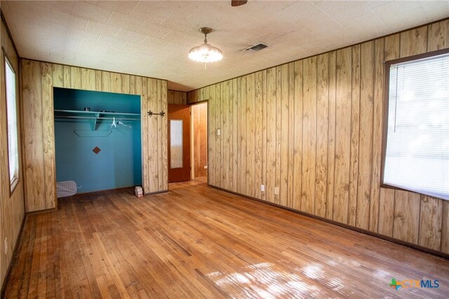 unfurnished bedroom with hardwood / wood-style flooring, a closet, and wood walls