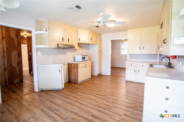 kitchen featuring tasteful backsplash, white cabinetry, sink, and light wood-type flooring