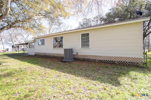 rear view of house featuring central AC unit and a yard