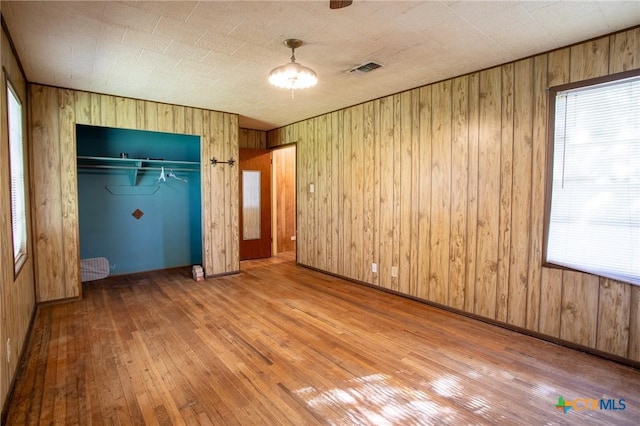 unfurnished bedroom featuring hardwood / wood-style floors, wooden walls, and a closet