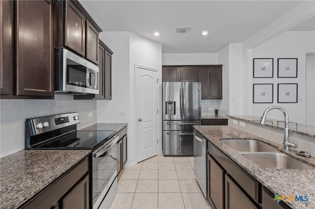 372 Poplin Ln, Troy, TX 76579 - kitchen with appliances with stainless steel finishes, a sink, dark brown cabinets, tasteful backsplash, and dark stone countertops