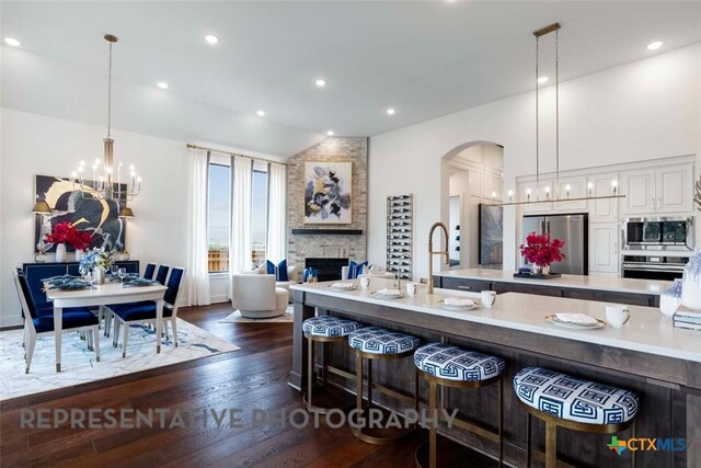 435 Nash Way, New Braunfels, TX 78130 - kitchen with dark hardwood / wood-style floors, pendant lighting, a stone fireplace, a breakfast bar area, and stainless steel appliances