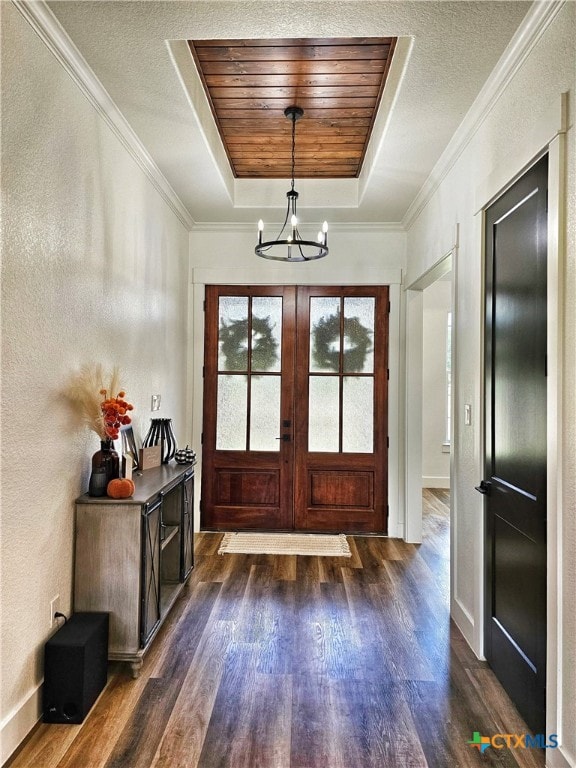 doorway featuring french doors, a raised ceiling, dark hardwood / wood-style flooring, a notable chandelier, and crown molding