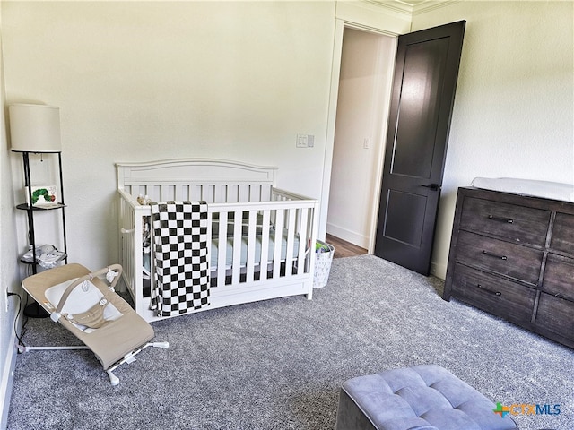 carpeted bedroom featuring a nursery area and crown molding