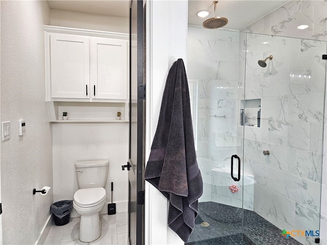 bathroom featuring a shower with door and toilet