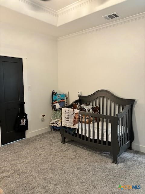 carpeted bedroom featuring a tray ceiling, crown molding, and a nursery area