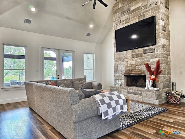 living room featuring ceiling fan, french doors, a stone fireplace, hardwood / wood-style floors, and vaulted ceiling