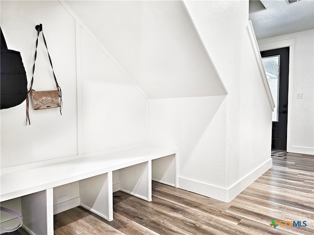 mudroom featuring wood-type flooring, a textured ceiling, and vaulted ceiling