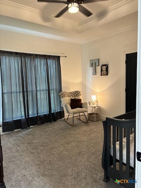 carpeted bedroom with a raised ceiling, ceiling fan, crown molding, and a crib