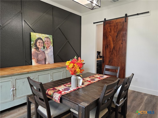 dining area featuring a barn door, hardwood / wood-style flooring, and crown molding