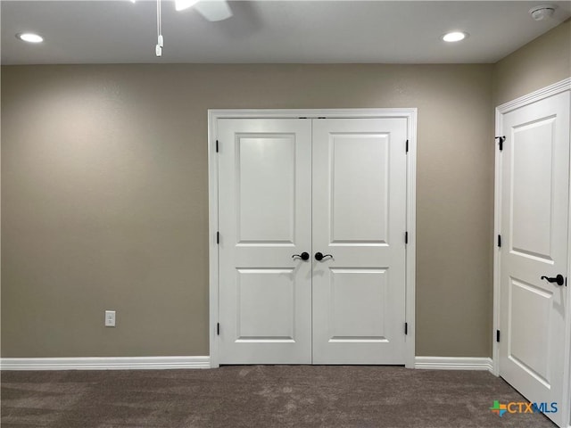 unfurnished bedroom with a closet, dark carpet, and ceiling fan