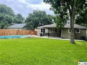 back of property with a fenced in pool and a yard