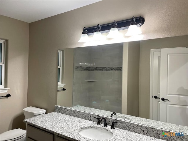 bathroom featuring vanity, toilet, and tiled shower