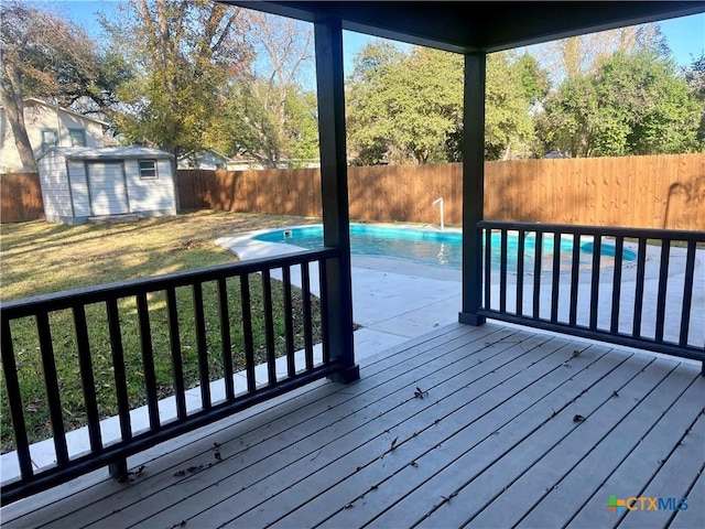 deck featuring a lawn, a fenced in pool, and a shed