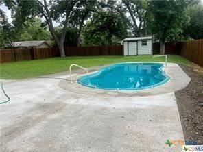 view of swimming pool with a lawn, a patio, and a storage unit