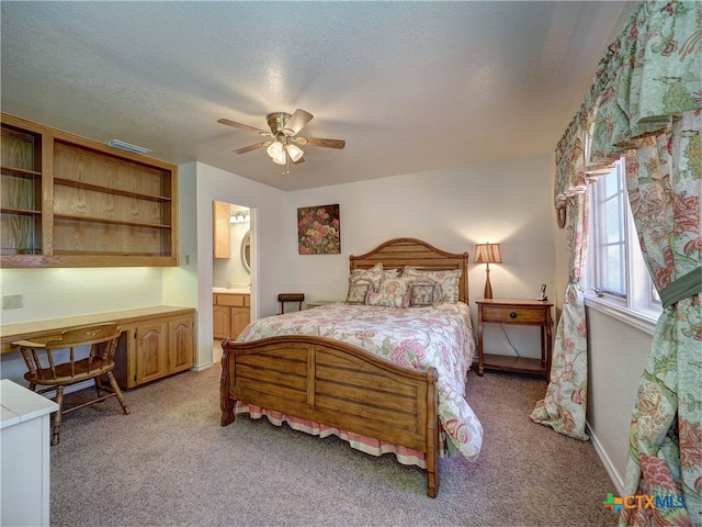 bedroom featuring light carpet, connected bathroom, built in desk, and ceiling fan