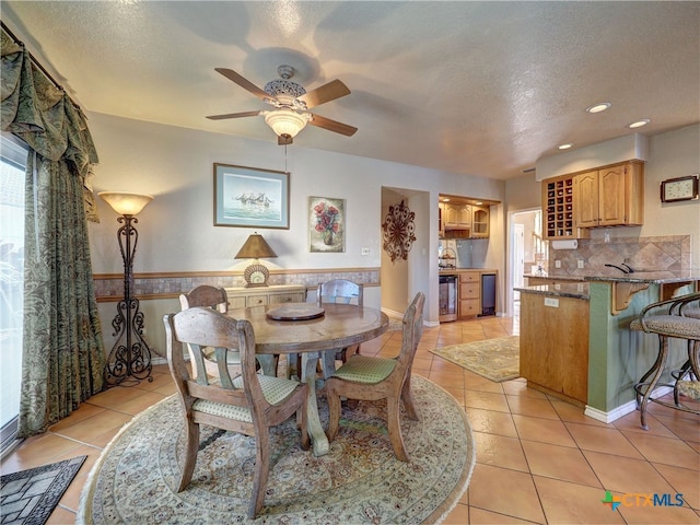 dining area with ceiling fan, sink, light tile patterned floors, and a textured ceiling