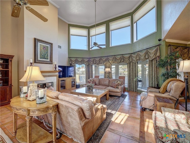 living room with a high ceiling, ornamental molding, tile patterned flooring, and ceiling fan