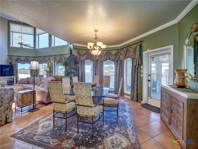 dining space featuring light tile patterned floors, crown molding, ceiling fan with notable chandelier, and a textured ceiling