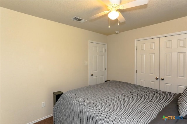 bedroom with a closet, dark colored carpet, visible vents, and ceiling fan