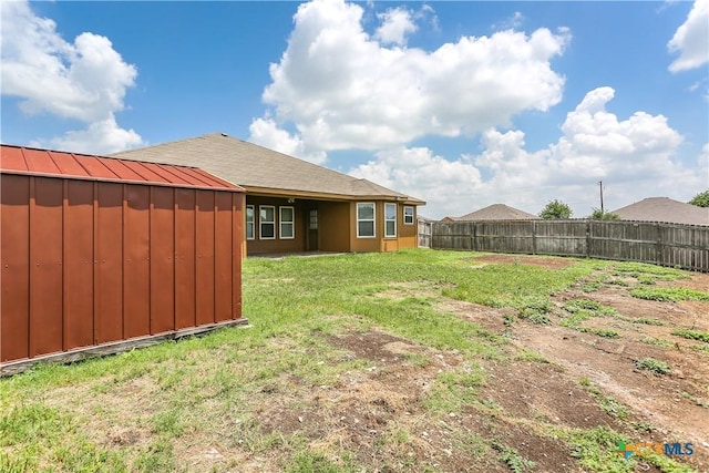 view of yard featuring a fenced backyard, a storage shed, and an outbuilding