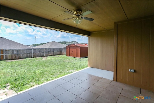 view of yard featuring a storage unit, a patio, an outbuilding, a fenced backyard, and a ceiling fan