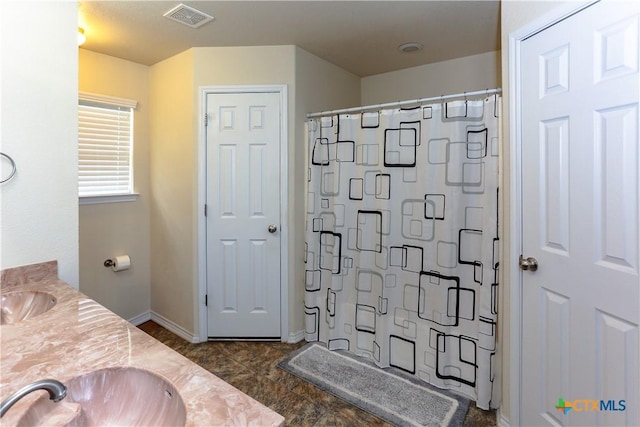 bathroom featuring a sink, a shower with curtain, visible vents, double vanity, and baseboards